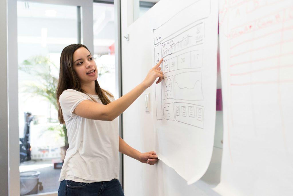 woman standing pointing paper on board